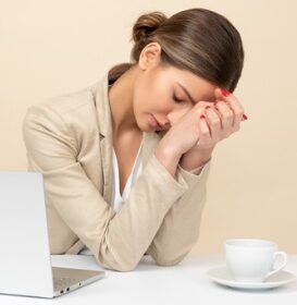 woman sitting by computer looks tired