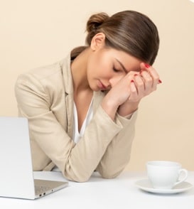 woman sitting by computer looks tired